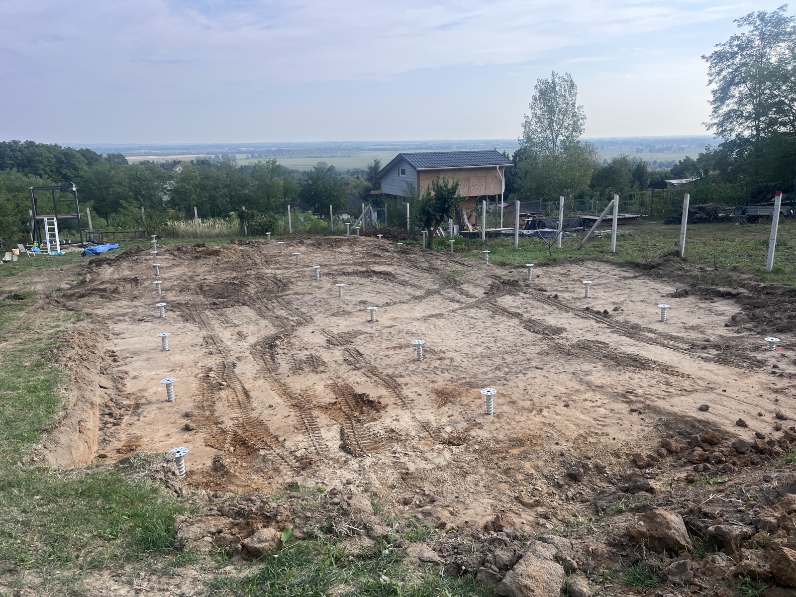 Kész talajcsavarmező az egyik telkünkön, állítható fejlemezekkel, kiszintezve. Jól látszik a szabályos raszterkiosztás: ez mért és tervezett alapozás, nem néhány leütött cölöp.