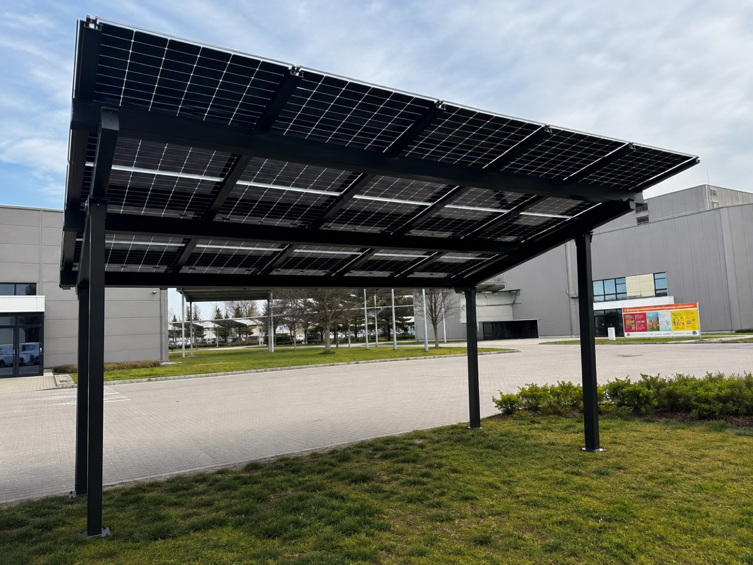 Napelemes autóbeálló. A parkoló felülete addig kihasználatlan volt; itt egyszerre ad árnyékot, védi az autót és termel — és ha a tetőn nincs elég hely, ez pótolja.